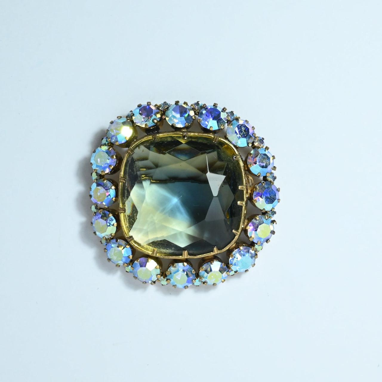 Bi colour vintage glass brooch with square blue green central stone surrounded by blue Ab glass claw set stones gold plated