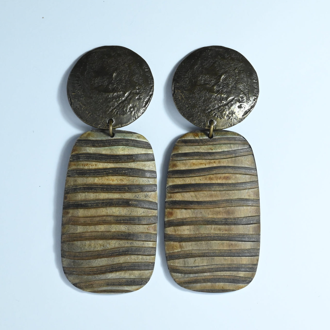 Large brown statement earrings by Parisian designer Cesaree from the 1980s with a circular bronze coloured clip on top and a large furrowed wooden drop.